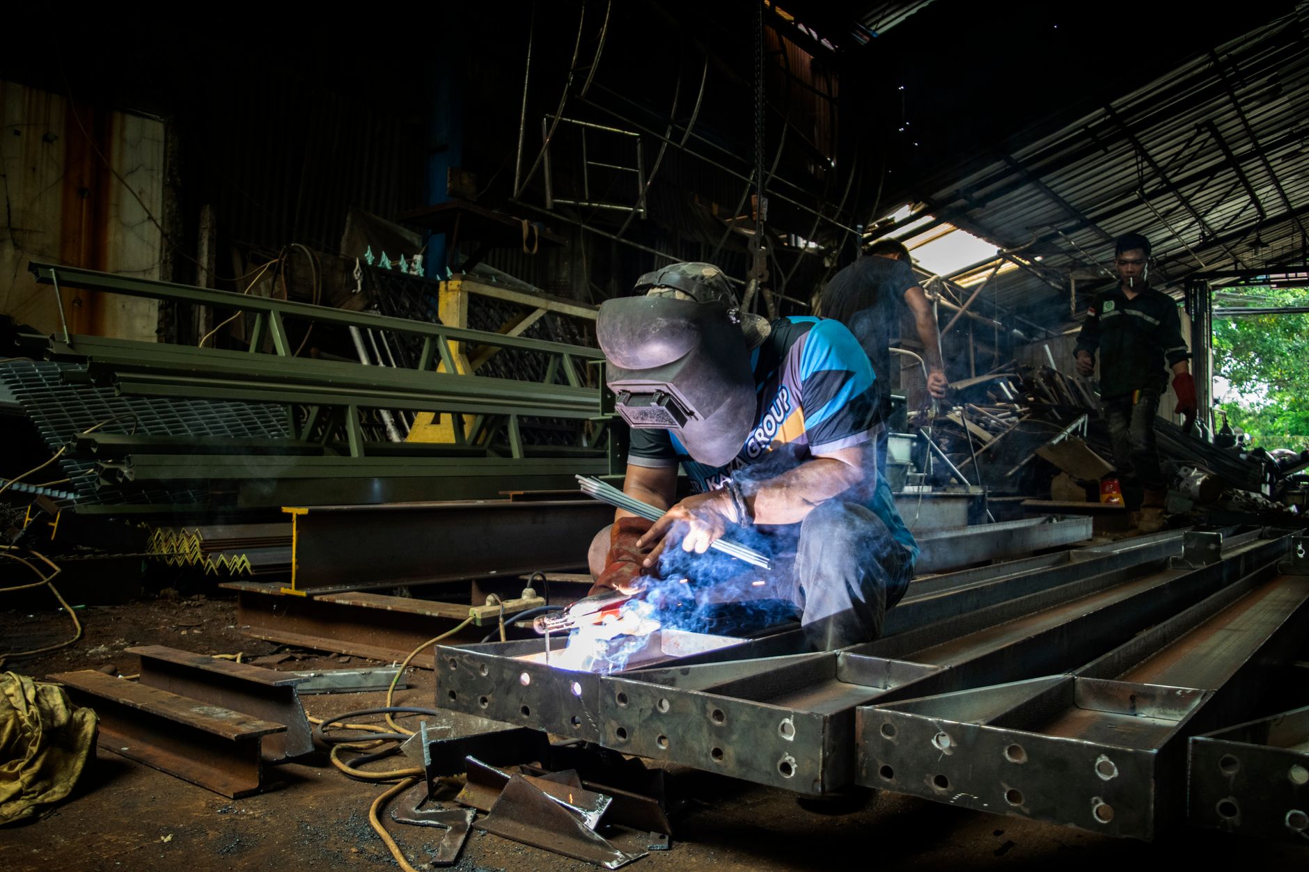 Student in a welding helmet and protective gloves operating an arc welder in a school workshop