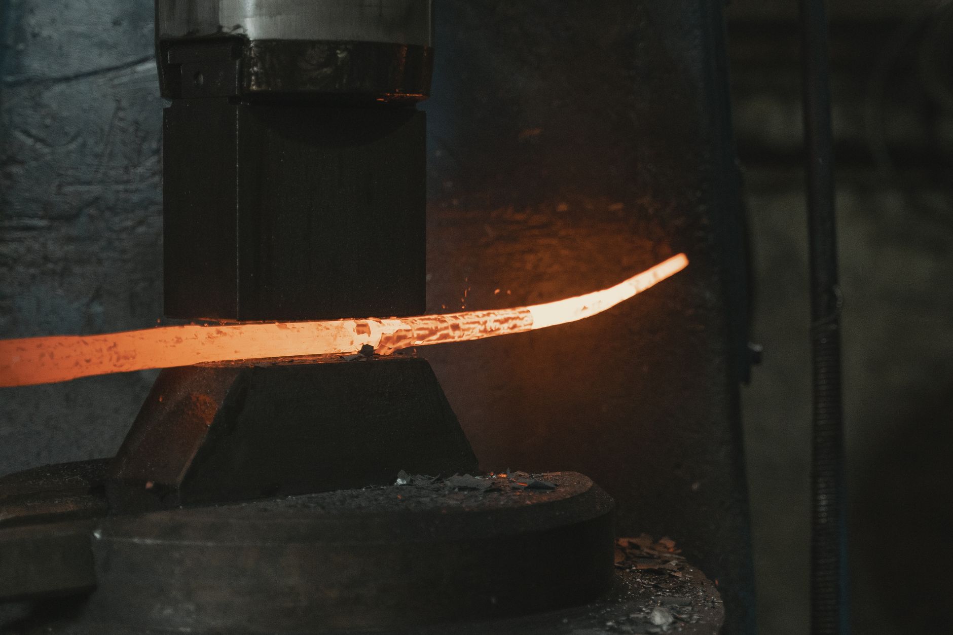 Iron meteorite fragment resting beside a blacksmith's anvil and tongs in a workshop
