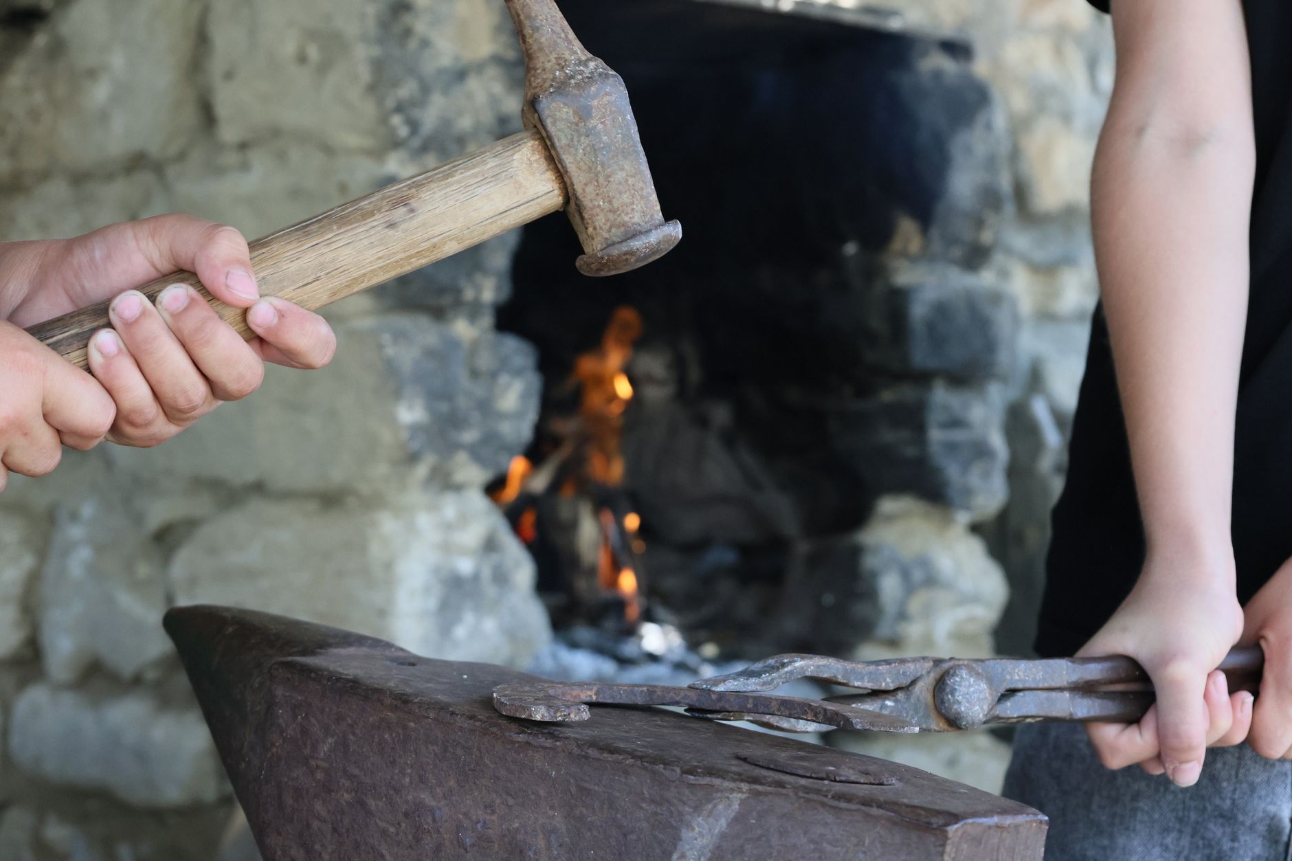 Bladesmith working at a coal forge inside a wood-framed workshop in Junction City, Oregon